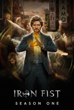 Finn Jones in a suit with a glowing gold fist held forward, a Manhattan skyline behind.