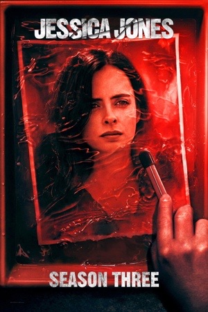 Krysten Ritter holding a torch, framed inside a red rectangle against black.