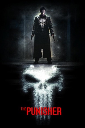 A man in a black coat with a skull on his chest, standing in a dark corridor above a huge painted skull.