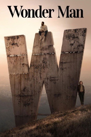 A man sitting on top of an enormous weathered concrete letter W on a hillside.